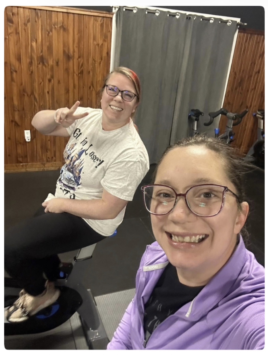 Two friends smiling together during a cycling class