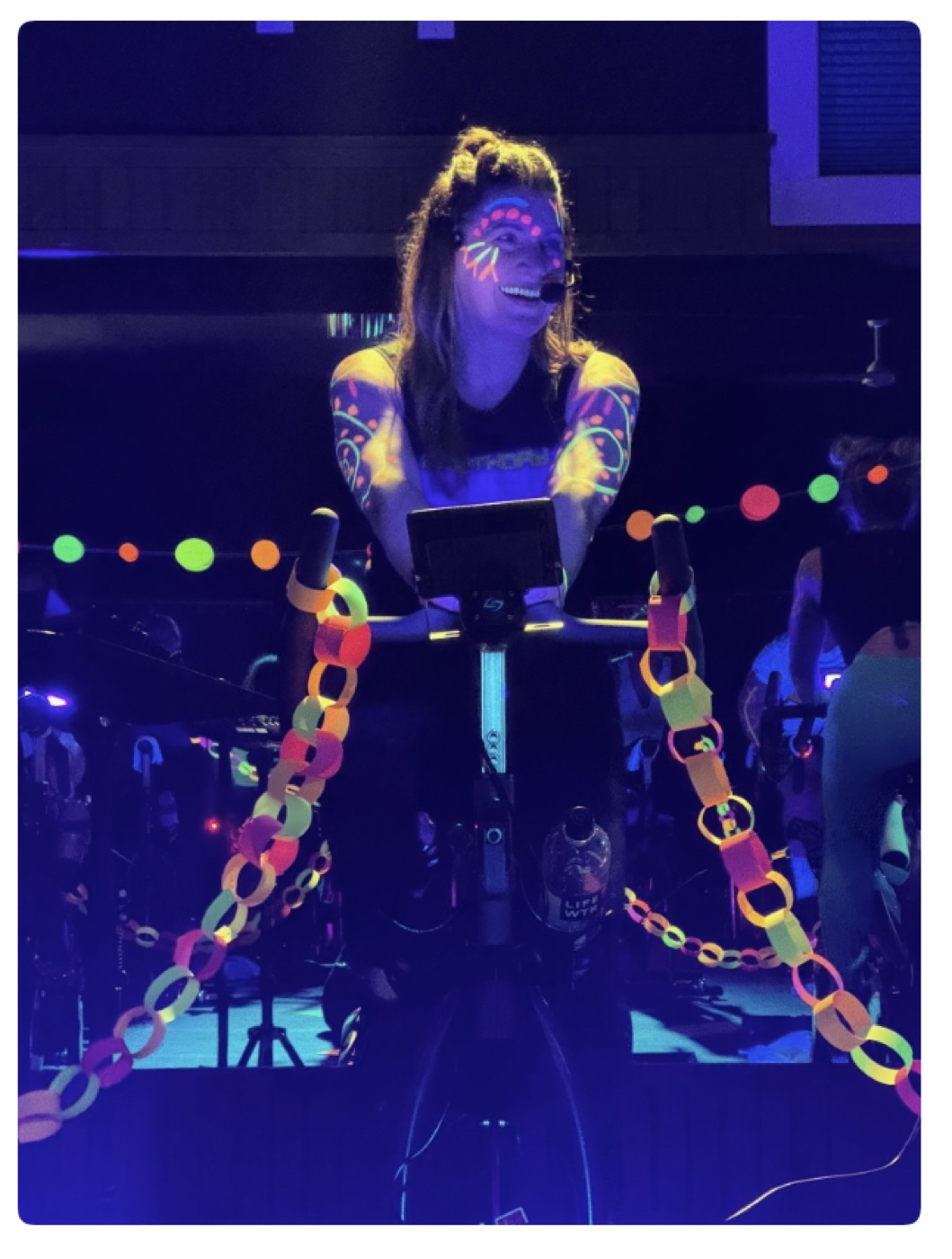 A cycling instructor leading a glow-themed class